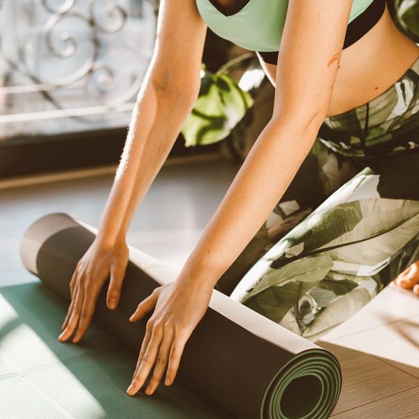 Person rolling out a yoga mat preparing for practice.
