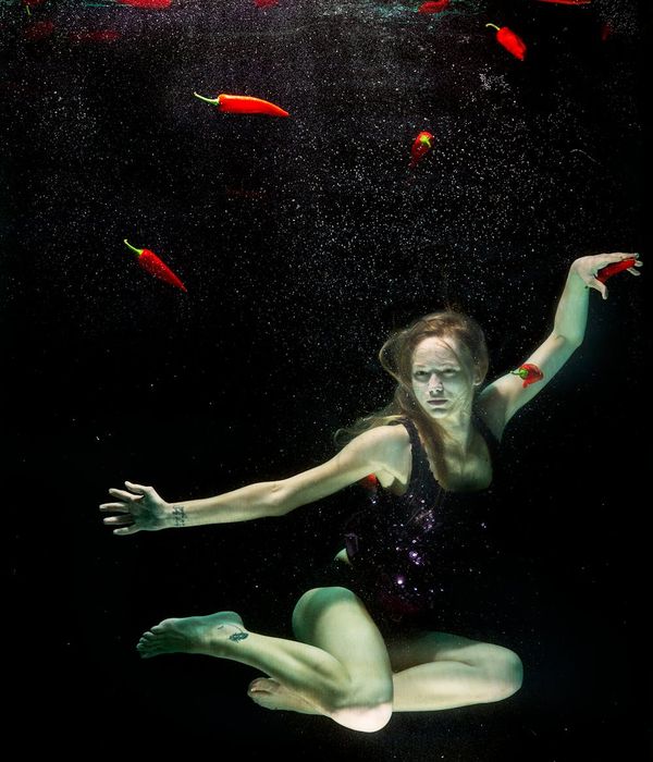 Woman in a fluid yoga pose on a dark background.